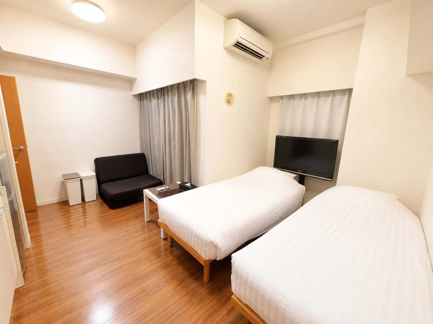 The room at D-Ryokan Kabukicho with two single beds, a sofa bed and a TV